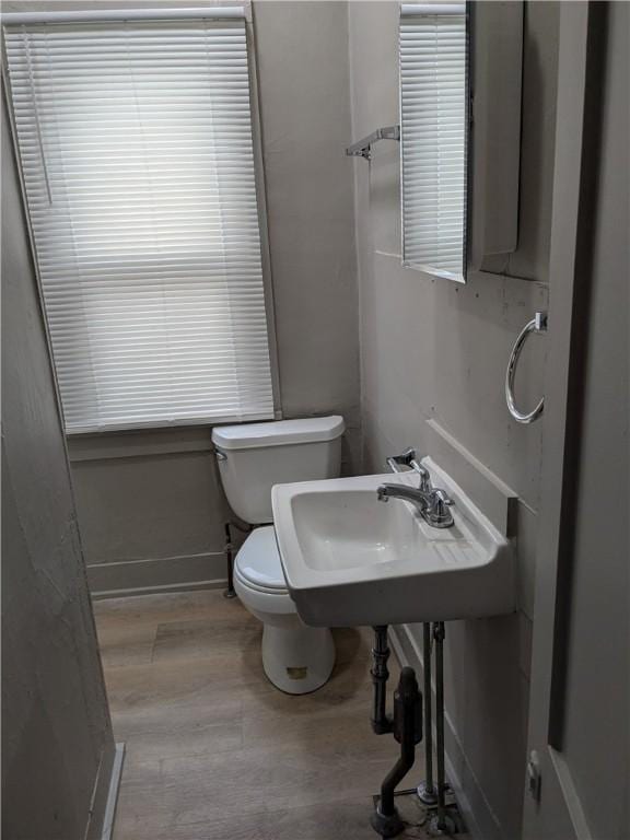 bathroom with toilet, a sink, baseboards, and wood finished floors