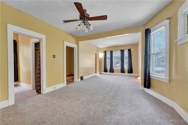 carpeted empty room featuring ceiling fan and a textured ceiling