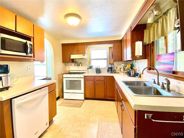 kitchen featuring tasteful backsplash, sink, white appliances, and exhaust hood