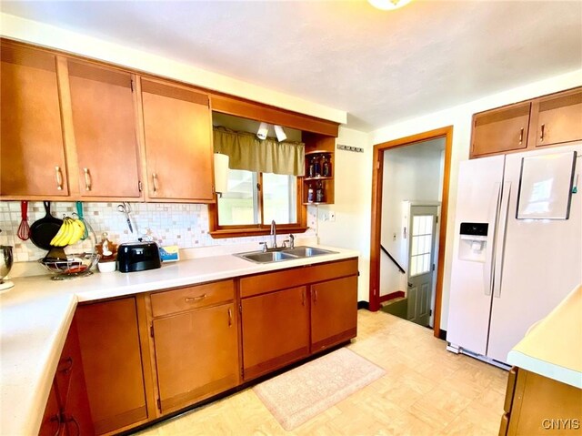 kitchen with sink, decorative backsplash, and white fridge with ice dispenser