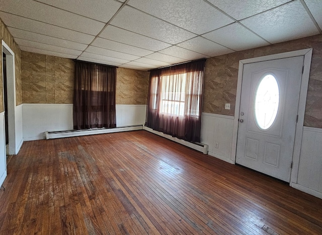 entrance foyer featuring dark hardwood / wood-style flooring, baseboard heating, and a drop ceiling