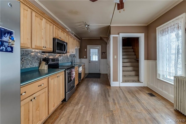 kitchen featuring radiator heating unit, sink, stainless steel appliances, light brown cabinets, and light hardwood / wood-style flooring