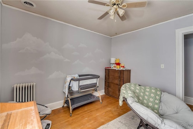 sitting room featuring crown molding, ceiling fan, wood-type flooring, and radiator