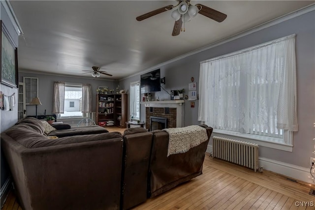 living room with light hardwood / wood-style flooring, a fireplace, radiator heating unit, and ornamental molding