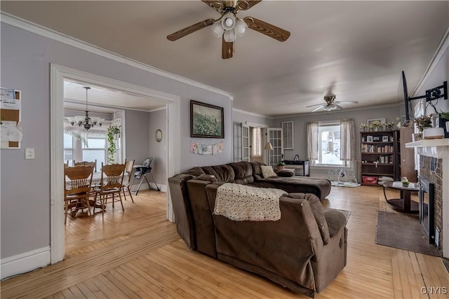 living room featuring crown molding, ceiling fan with notable chandelier, and light hardwood / wood-style flooring