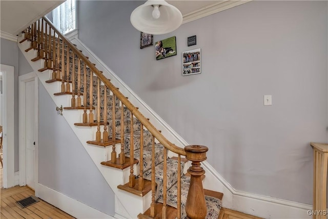 staircase with crown molding and wood-type flooring