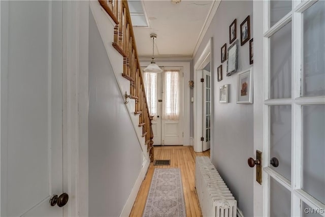 entryway featuring crown molding, radiator heating unit, and light hardwood / wood-style floors