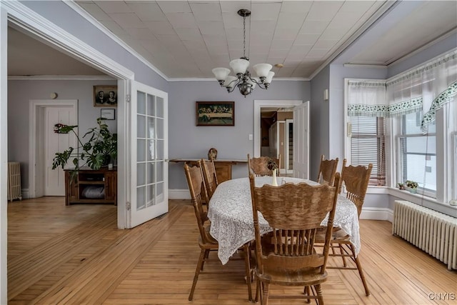 dining space featuring crown molding, radiator, and an inviting chandelier