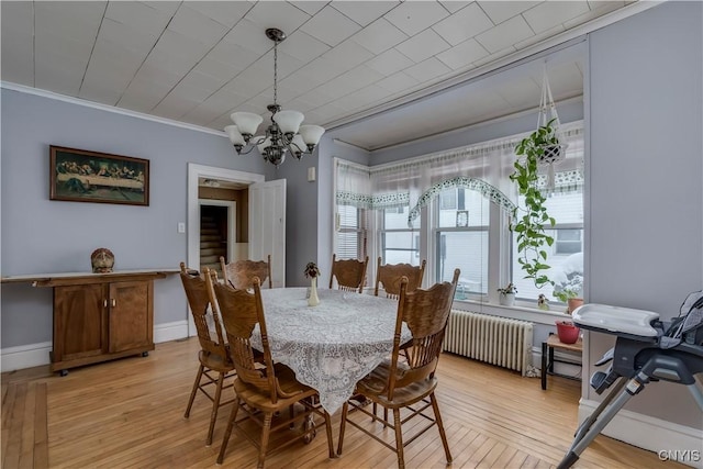 dining space with crown molding, radiator heating unit, an inviting chandelier, and light hardwood / wood-style floors