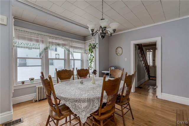 dining area featuring a healthy amount of sunlight, ornamental molding, radiator, and a chandelier