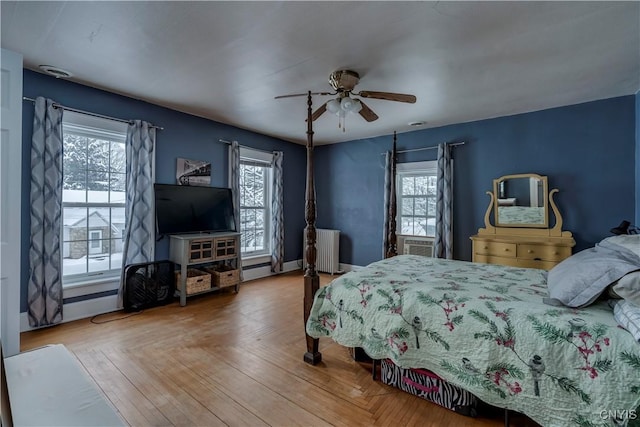 bedroom featuring multiple windows, parquet floors, radiator heating unit, and ceiling fan