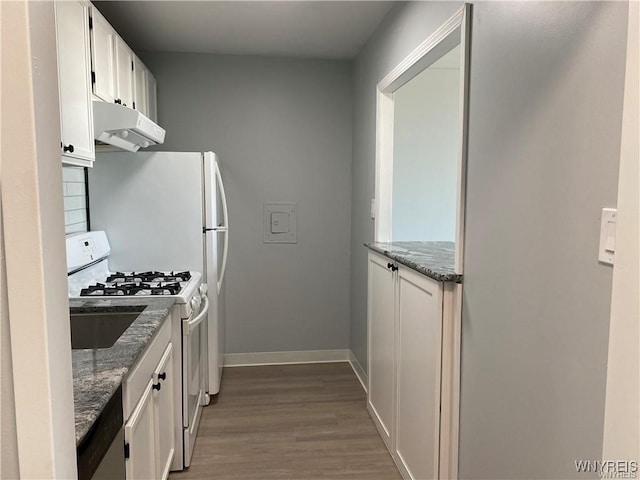 kitchen with white cabinetry, light hardwood / wood-style flooring, white range with gas cooktop, and dark stone counters