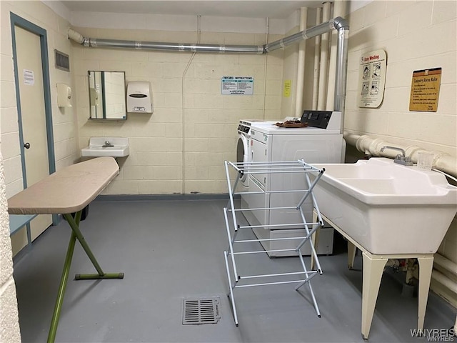 miscellaneous room featuring independent washer and dryer, sink, and concrete floors