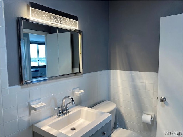 bathroom with vanity, tile walls, and toilet