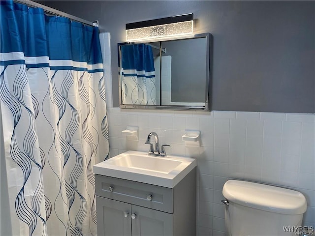 bathroom with vanity, toilet, and tile walls