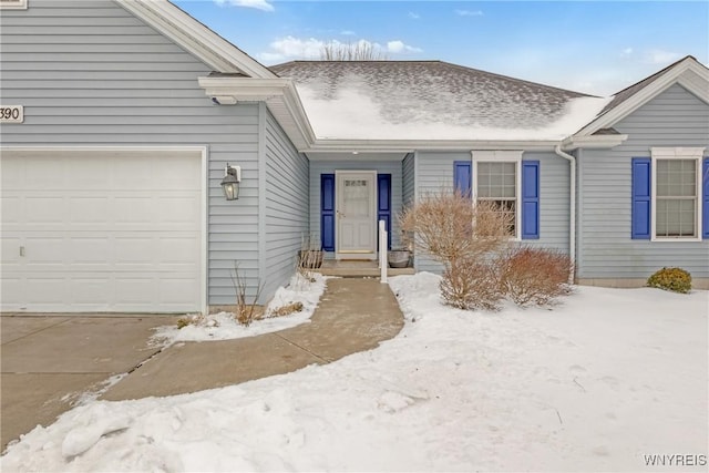 snow covered property entrance with a garage