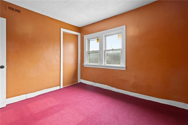 empty room with carpet floors and a textured ceiling