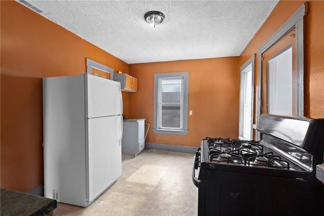 kitchen featuring white refrigerator, black range with gas cooktop, and a textured ceiling