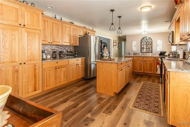 kitchen featuring appliances with stainless steel finishes, a kitchen island, decorative light fixtures, kitchen peninsula, and light stone countertops