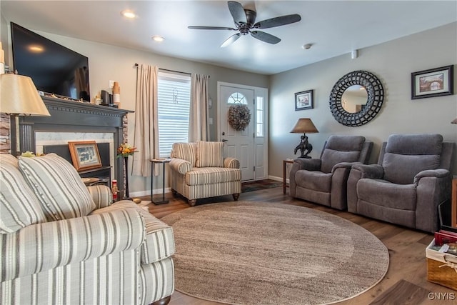 living room featuring a high end fireplace, wood-type flooring, and ceiling fan