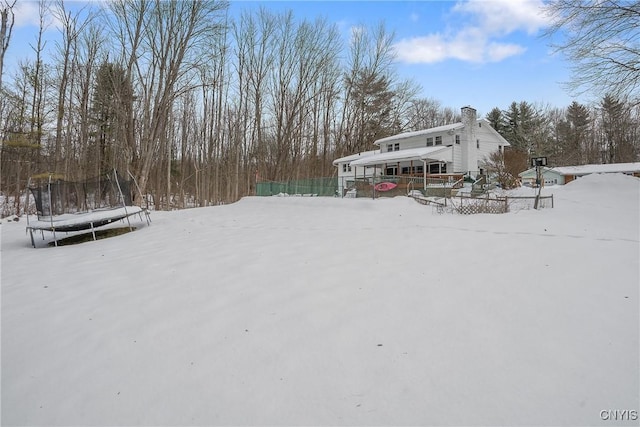 yard layered in snow featuring a trampoline