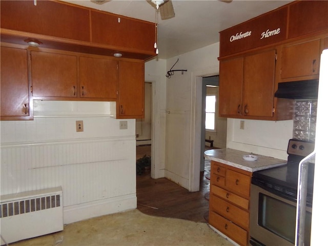 kitchen with brown cabinets, electric stove, under cabinet range hood, and radiator