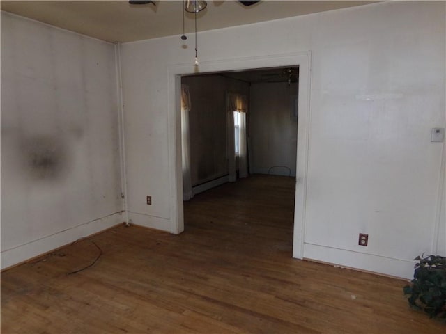 spare room featuring baseboards, baseboard heating, and wood finished floors