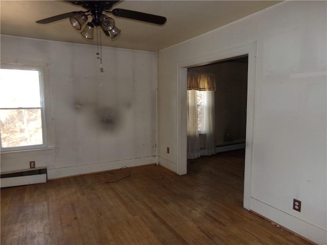 spare room with a baseboard radiator, a baseboard heating unit, baseboards, wood finished floors, and a ceiling fan