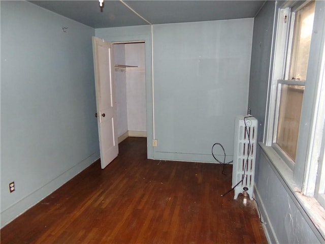 unfurnished bedroom featuring radiator heating unit, wood finished floors, and baseboards