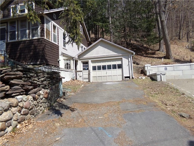 view of home's exterior with a detached garage, aphalt driveway, and an outbuilding