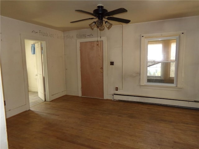 spare room featuring baseboard heating, wood finished floors, and a ceiling fan
