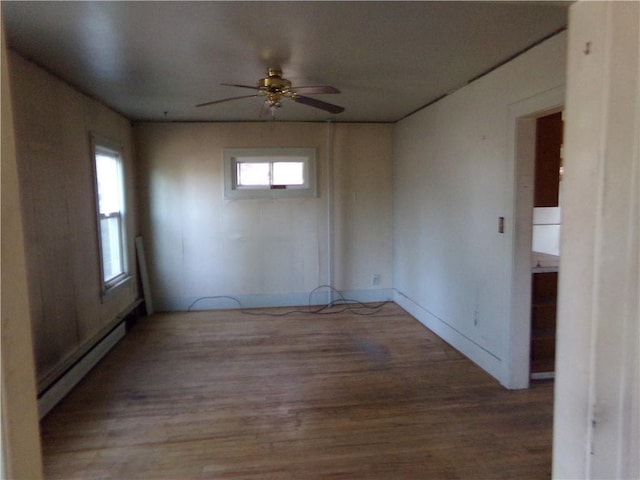 spare room featuring wood finished floors, a ceiling fan, and baseboard heating