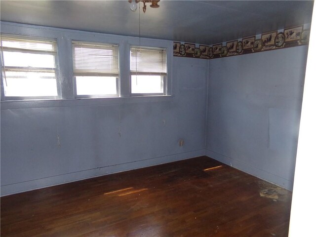 spare room featuring baseboards and dark wood-style flooring