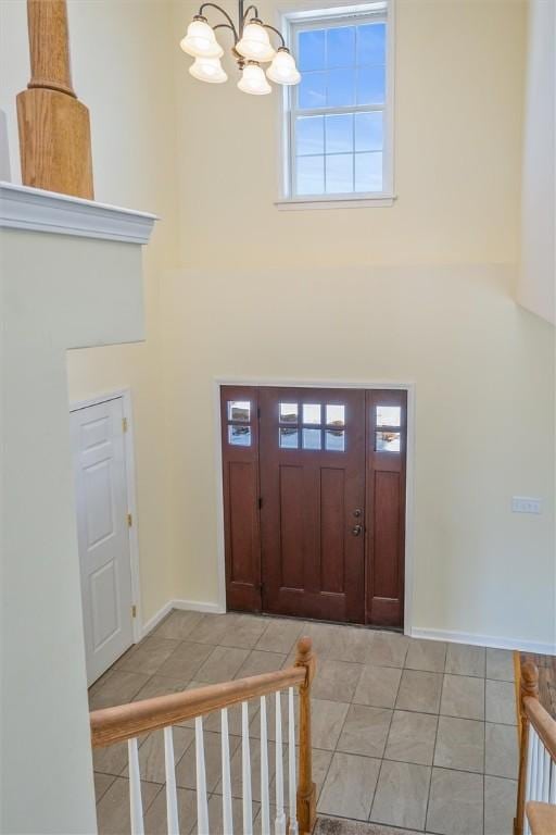 tiled foyer featuring an inviting chandelier and a towering ceiling