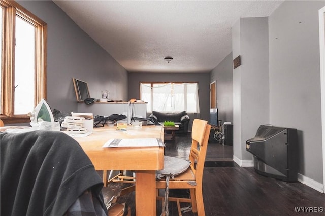 dining space with dark wood-type flooring and a textured ceiling