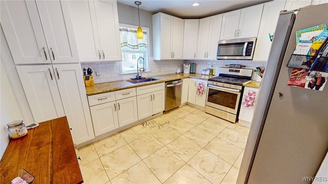 kitchen with sink, white cabinetry, decorative light fixtures, stainless steel appliances, and light stone countertops