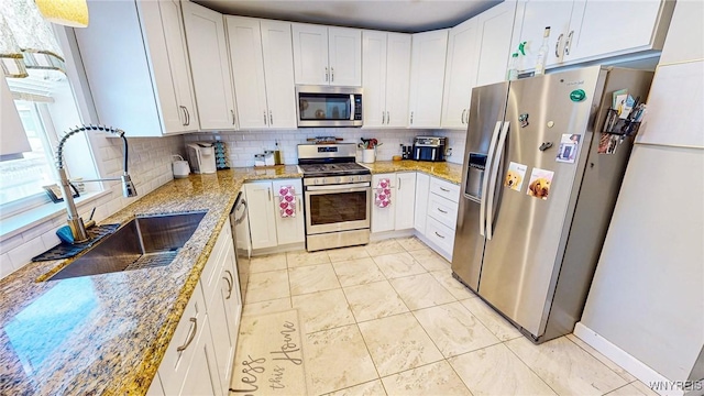 kitchen with white cabinetry, light stone countertops, appliances with stainless steel finishes, and sink