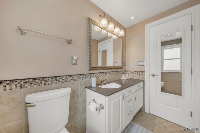 bathroom featuring vanity, tile walls, tile patterned floors, and toilet