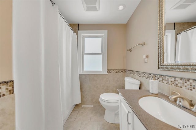 bathroom featuring vanity, toilet, tile patterned flooring, and tile walls