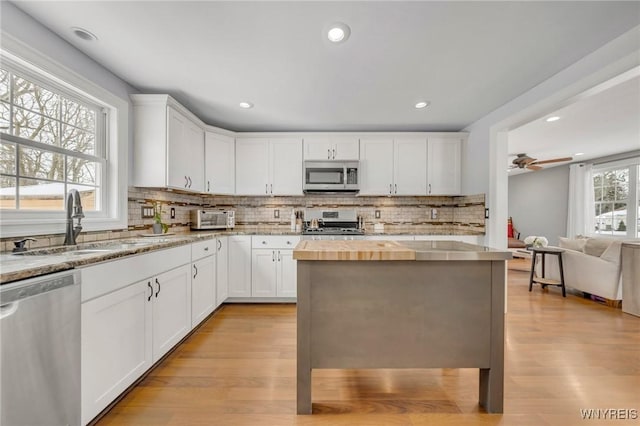 kitchen featuring sink, white cabinets, ceiling fan, stainless steel appliances, and light hardwood / wood-style flooring