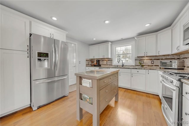 kitchen with decorative backsplash, stainless steel appliances, white cabinets, and light wood-type flooring