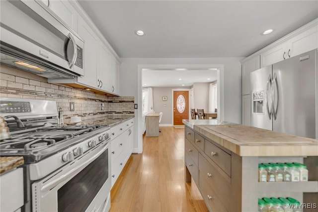 kitchen featuring wooden counters, light hardwood / wood-style flooring, appliances with stainless steel finishes, white cabinets, and backsplash