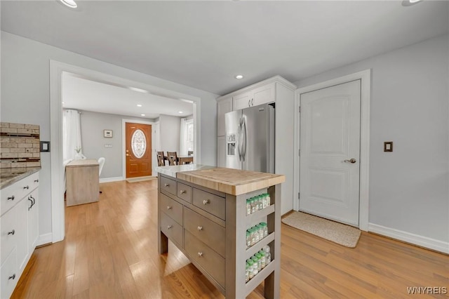 kitchen with light hardwood / wood-style flooring, backsplash, stainless steel fridge, and white cabinets