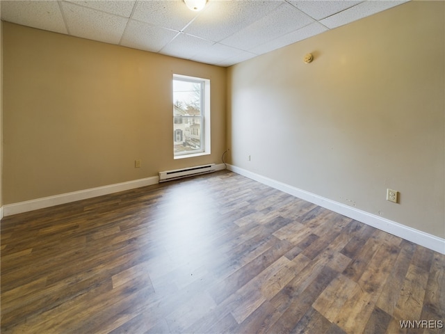 spare room featuring dark hardwood / wood-style floors, a paneled ceiling, and baseboard heating