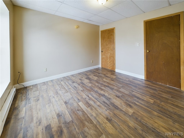 spare room featuring a baseboard radiator, a paneled ceiling, and dark hardwood / wood-style flooring