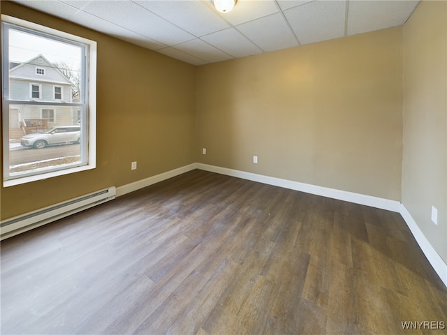 spare room with a baseboard heating unit, wood-type flooring, and a drop ceiling