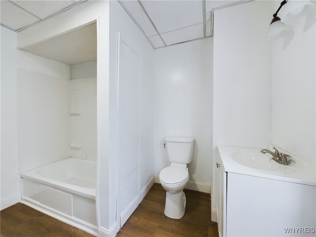 full bathroom with  shower combination, vanity, wood-type flooring, a drop ceiling, and toilet