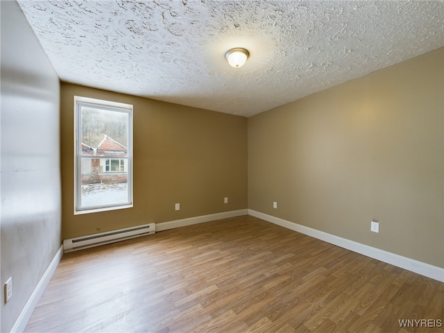 unfurnished room with a textured ceiling, baseboard heating, and light hardwood / wood-style flooring