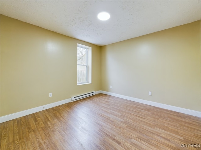 unfurnished room featuring light wood-type flooring, a textured ceiling, and a baseboard heating unit