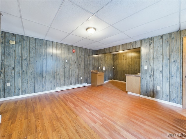 interior space with baseboard heating, a paneled ceiling, and hardwood / wood-style floors